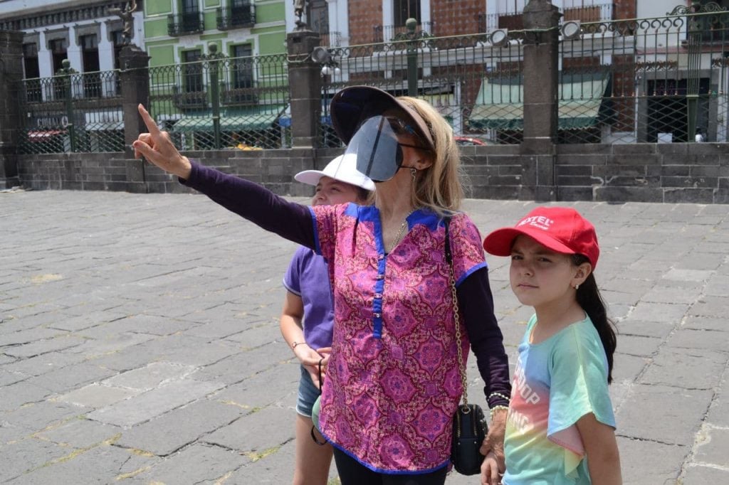 Muier con careta y cubrebocas con dos niñas en la Catedral del Centro Histórico Puebla