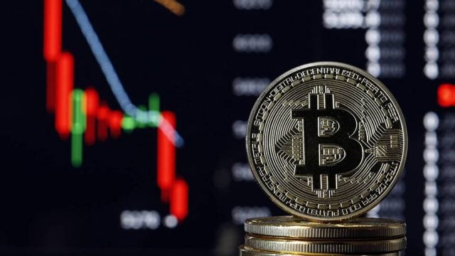 Se muestra una moneda de bitcoin y atrás se ve una gráfica que va bajando