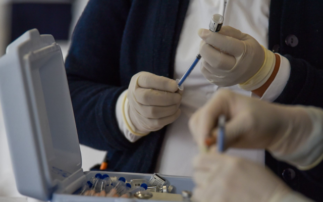 Se muestran a dos personas preparando jeringas con vacunas